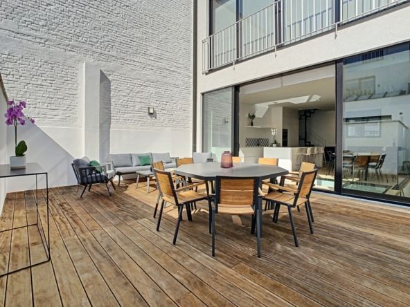 Stijlvol modern terras met houten meubels, lichttherapie en open uitzicht op het lichte interieur.