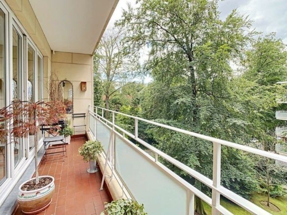 Balcon paisible avec plantes, mobilier confortable et vue sur une forêt verdoyante.