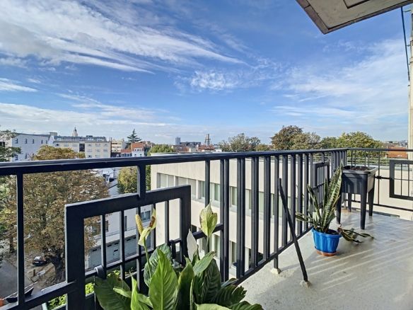 Balcon moderne sur la ville avec plantes vertes, ciel bleu, vue panoramique urbaine et harmonie.
