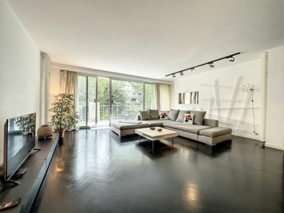 Salon moderne minimaliste avec vue lumineuse, canapé gris, mobilier épuré et décoration élégante.
