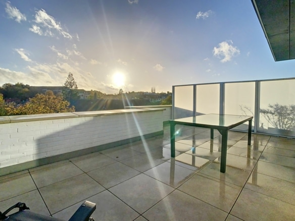 Terrasse au coucher du soleil avec vue panoramique, mobilier minimaliste et ambiance sereine.