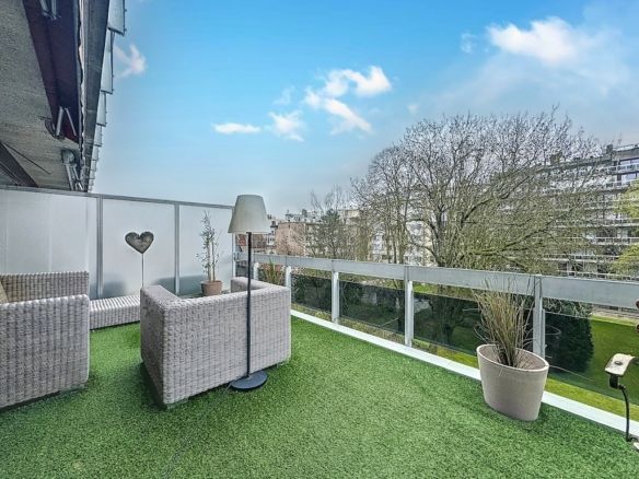 Balcon moderne avec pelouse artificielle, mobilier cosy et vue urbaine, parfait pour se détendre.