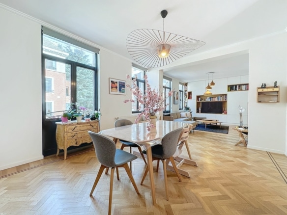 Salon moderne lumineux avec grande table en bois, vue sur la nature et décoration élégante.