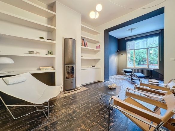 Salon moderne minimaliste avec mur bleu, meubles épurés, cheminée noire et lumière naturelle abondante.