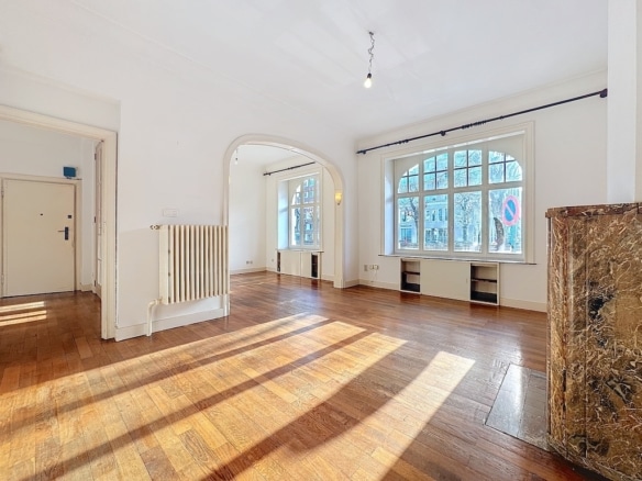 Intérieur lumineux et minimaliste avec hauts plafonds, grandes fenêtres, sol en bois et colonne en pierre.