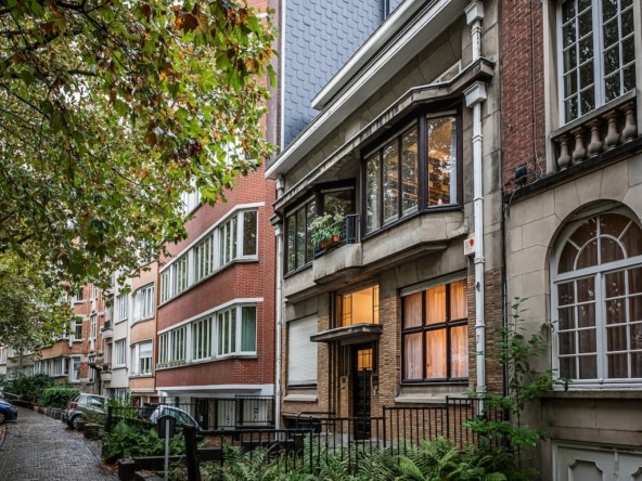 Een stedelijke straat die historische en moderne architectuur combineert, met groen, zachte verlichting en een vredige sfeer.