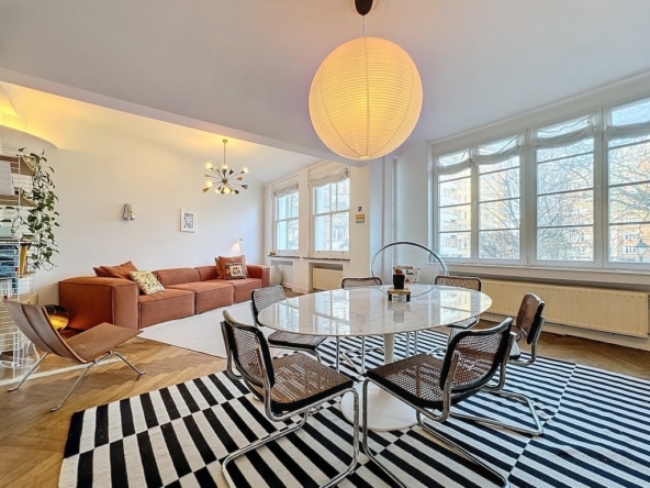 Moderne woonkamer met warme verlichting, designmeubels, planten, lichte en vriendelijke eethoek.