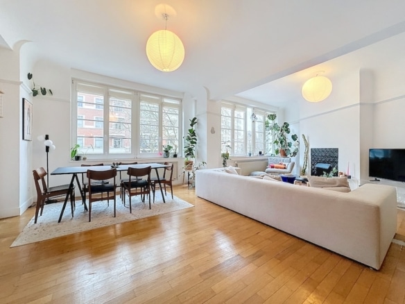 Salon contemporain lumineux avec canapé, table à manger en bois et décor végétal chaleureux.