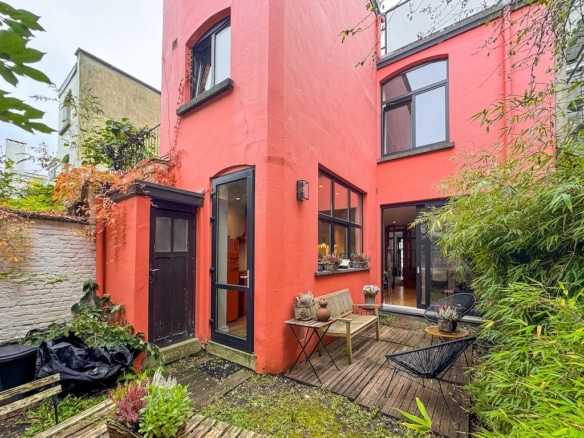 Maison moderne colorée avec terrasse en bois et jardin zen luxuriant.