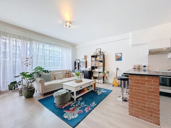 Moderne woonkamer met veel daglicht, gezellig meubilair, open keuken en elegante inrichting.