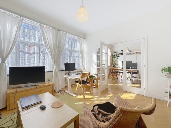 Lichte, moderne woonkamer met werkruimte, groene planten en natuurlijke toegang tot de tuin.