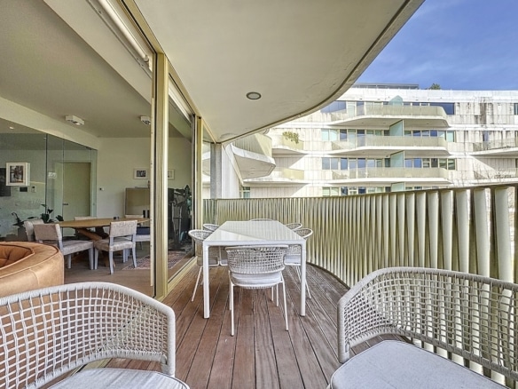Balcon moderne avec espace repas, lounge cosy, vue urbaine, design minimaliste et luminosité naturelle.