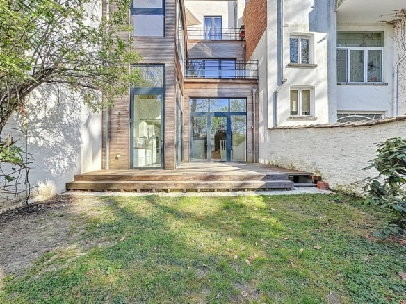 Maison contemporaine en verre avec jardin, escaliers en bois et design moderne harmonieux.