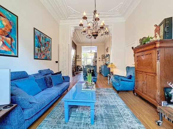 Salon cosy en bleu avec meubles élégants, œuvres d’art colorées et éclairage chaleureux.