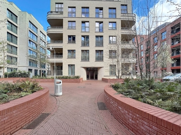 Résidence moderne avec jardins, chemins en briques, balcons lumineux, dans un cadre urbain verdoyant.