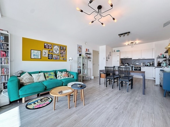 Salon contemporain avec canapé teal, déco colorée, espace repas moderne et cuisine blanche élégante.