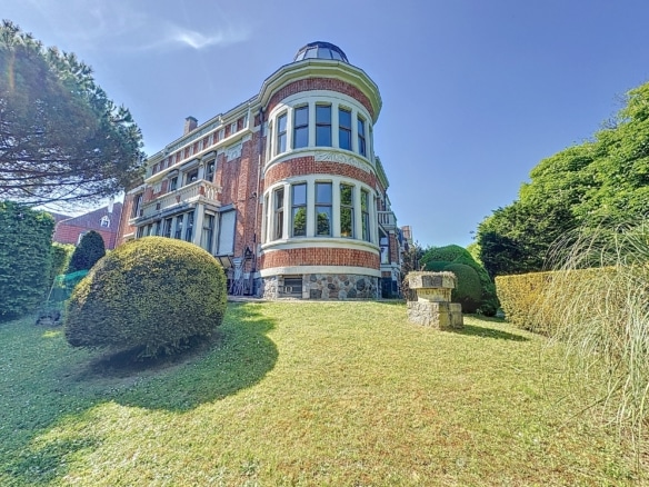 Villa de luxe avec dôme, jardins soignés, pelouses verdoyantes et arbres majestueux.