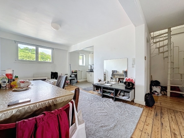 Lichte woonkamer met moderne meubels, open keuken, wenteltrap en gezellige inrichting.