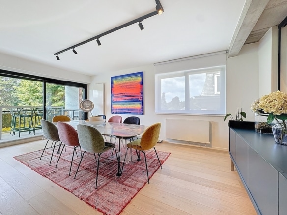 Salle à manger élégante lumineuse avec mobilier coloré, art abstrait, vue extérieure et décoration moderne.