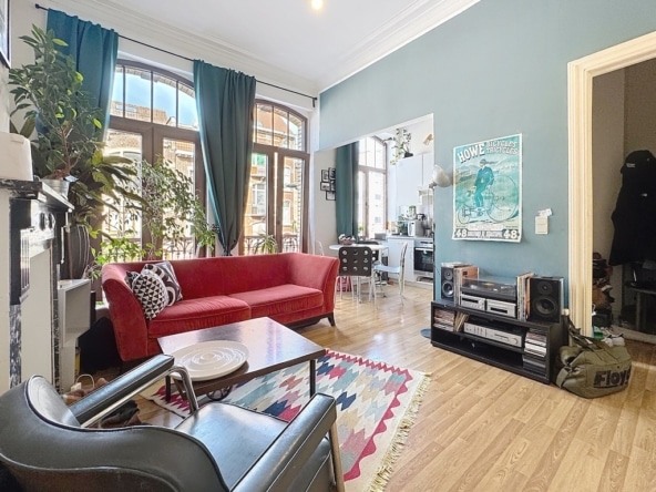 Lichte woonkamer met rode bank, planten, kleurrijk tapijt en eclectische inrichting.