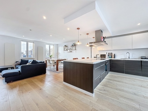 Salon et cuisine modernes, espace lumineux avec îlot blanc, canapé bleu foncé, vue panoramique.