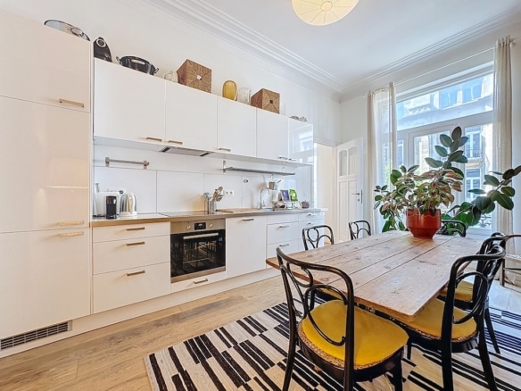 Cuisine moderne lumineuse avec mobilier blanc, table en bois et touches de couleur chaleureuses.