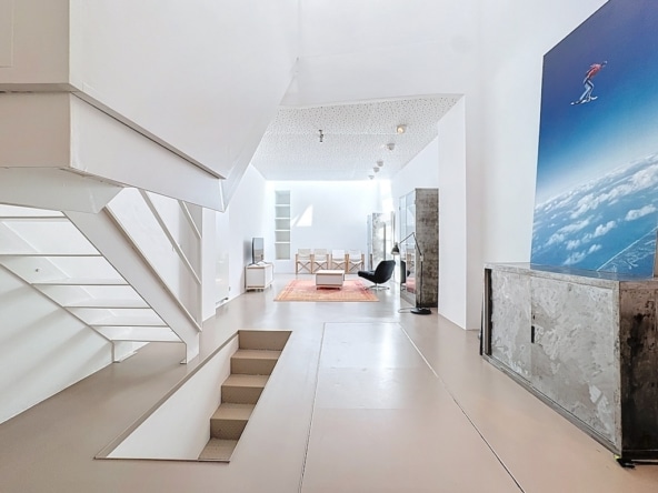 Helder modern interieur, witte zwevende trap, kleurrijk kunstwerk, open ruimte en strak design.