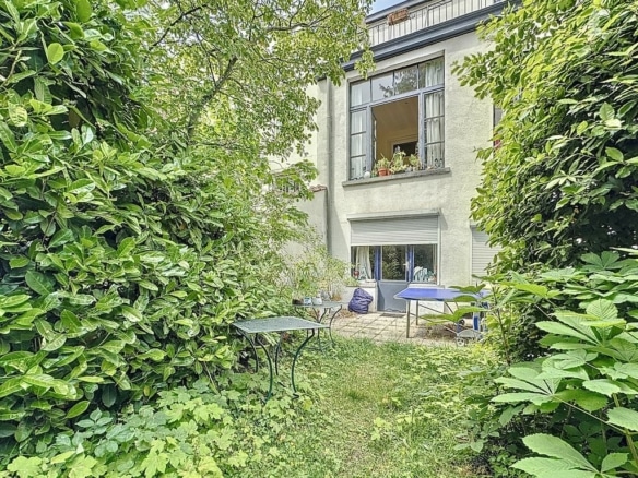 Jardin calme avec chemin bordé de verdure et fenêtre éclairée pour détente en plein air.
