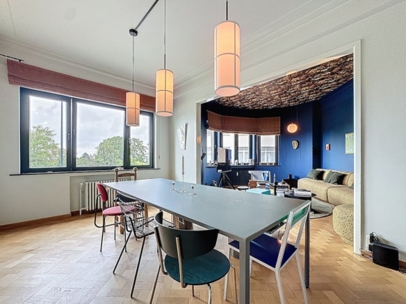 Salle à manger moderne avec table colorée, éclairage doux et espace cosy au mur bleu vif.