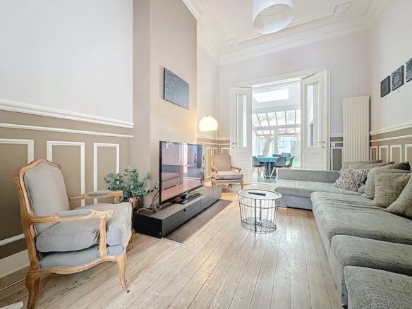 Salon lumineux et élégant avec mobilier moderne, moulures classiques et décoration raffinée.