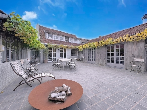 Cour intérieure cosy avec mobilier moderne, murs en bois rustique, végétation verdoyante et ambiance apaisante.