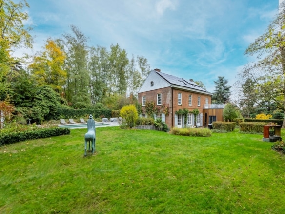Maison chaleureuse en briques avec jardin, sculpture de cheval, piscine et ambiance automnale.