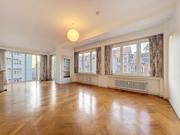 Salon spacieux lumineux avec parquet, grandes fenêtres, décoration élégante et ambiance chaleureuse.