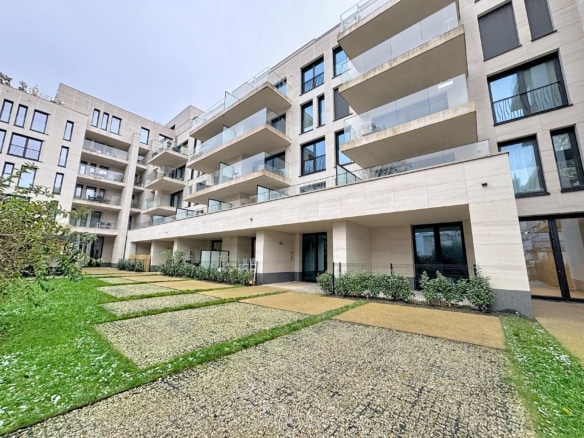 Appartement moderne avec balcons, jardin soigneusement aménagé et façade élégante en pierre claire.