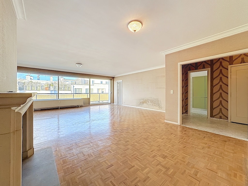 Salon lumineux avec grandes fenêtres, parquet en bois, espace moderne à Bruxelles.