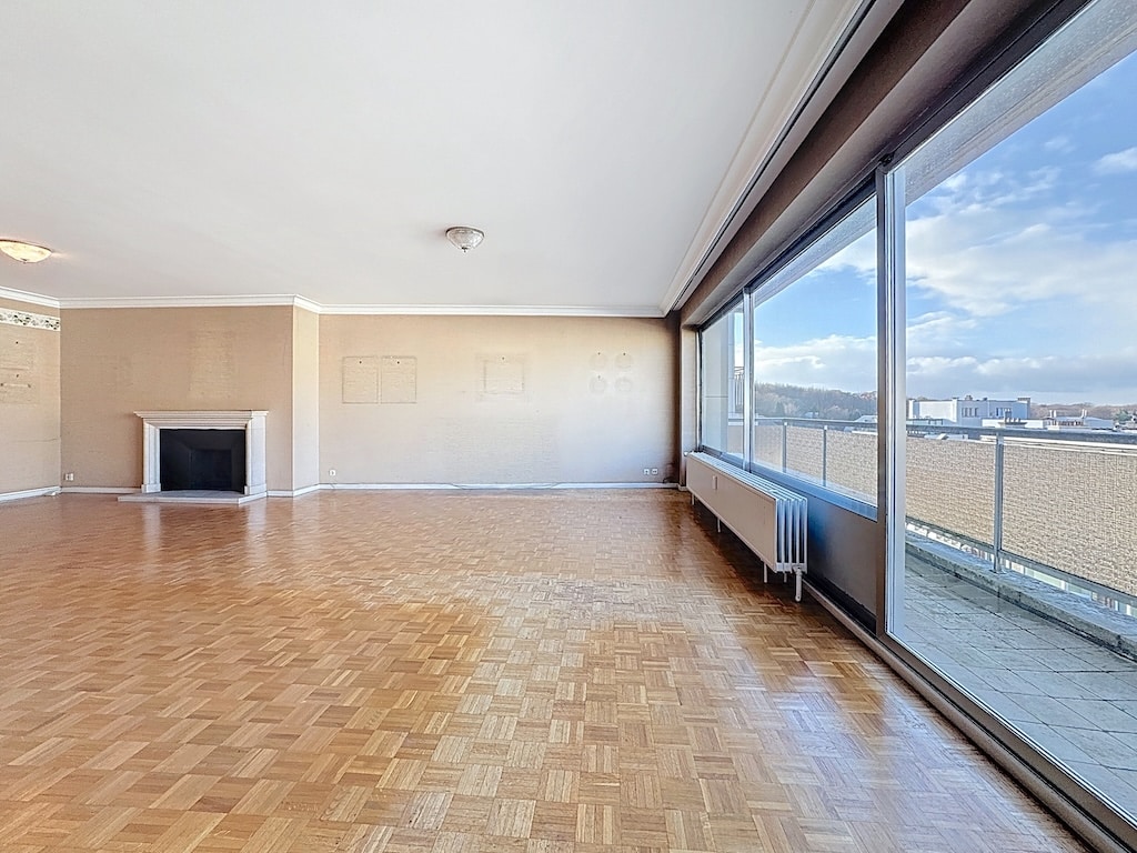 Espace de vie lumineux avec vue urbaine, parquet, cheminée moderne et accès terrasse à Bruxelles.