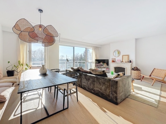 Salon moderne lumineux avec coin repas en bois, grande fenêtre, décoration minimaliste élégante.