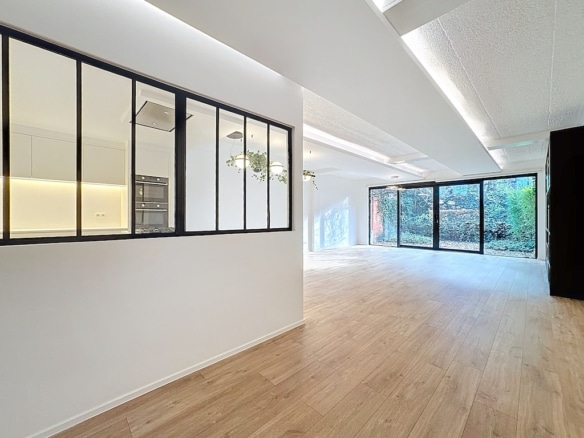 Salon moderne lumineux avec vue sur la nature et cuisine ouverte minimaliste.