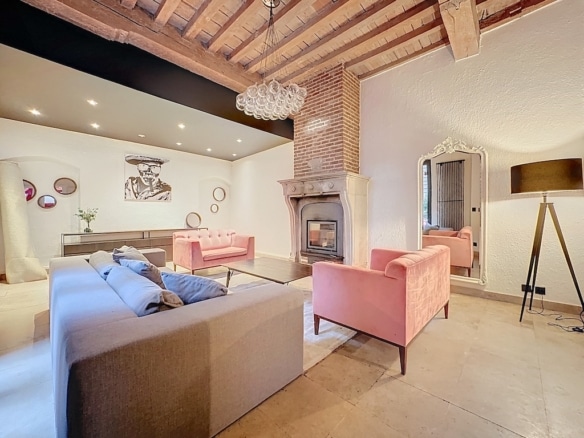 Salon contemporain chaleureux avec cheminée en briques, canapé gris et rose, décoration élégante.