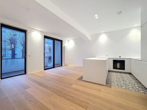 Intérieur moderne et épuré avec cuisine ouverte, grandes fenêtres, sol en bois clair et design minimaliste.