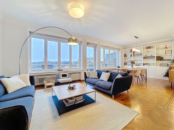 Salon contemporain avec vue panoramique, canapés bleus, éclairage chaleureux et décoration élégante.