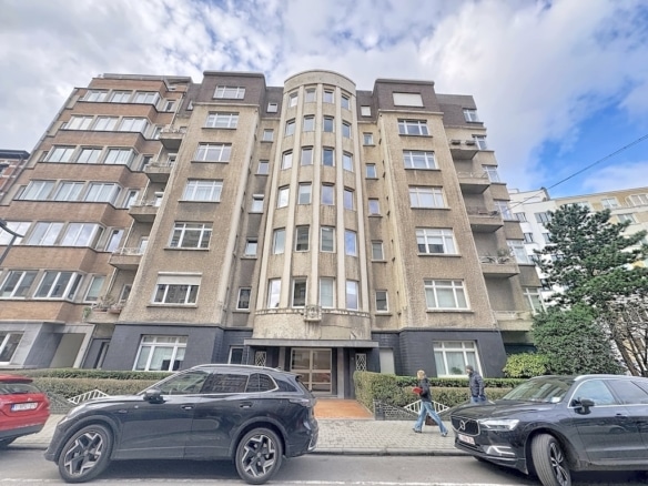 Immeuble résidentiel Art Déco avec tour arrondie, façade en brique, fenêtres élégantes, rue animée.