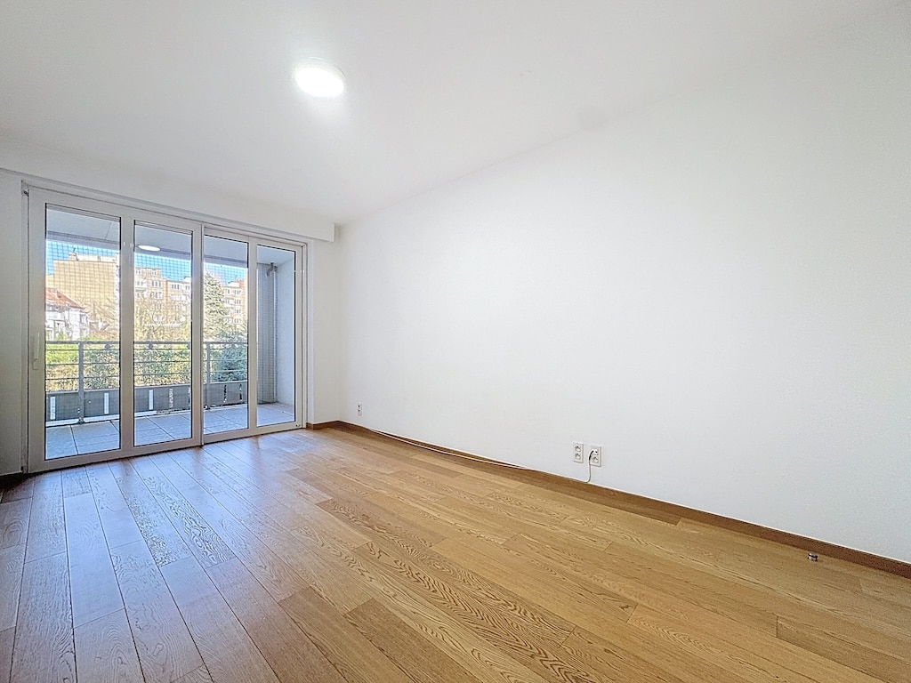 Lichte kamer met parketvloer, grote erker en uitzicht op buiten in Ukkel.