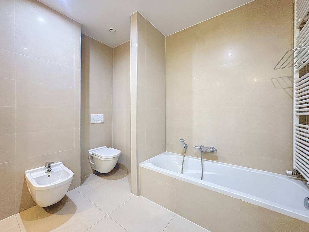 Moderne badkamer met bad, bidet, wandcloset en Brusselse radiator.