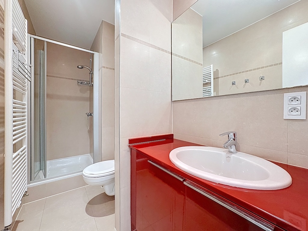 Moderne badkamer met douche, compacte WC en rode wastafel in Elsene.
