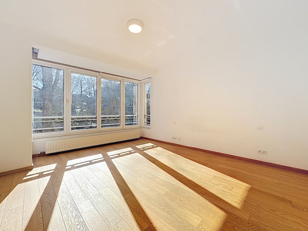 Licht interieur met grote ramen, lichtgekleurde houten vloeren, warme sfeer in Ukkel.