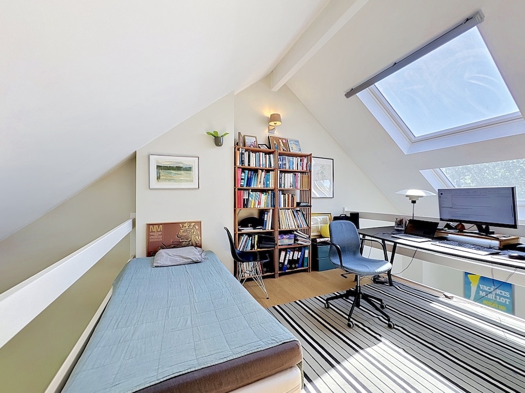 Chambre bureau mansardée à Londres avec lit simple, bibliothèque et fenêtres de toit