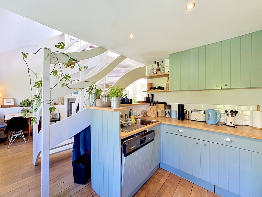 Cuisine ouverte lumineuse à Londres avec meubles bleu pastel et escalier blanc