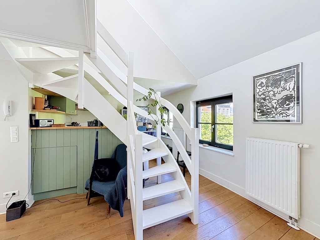 Pièce lumineuse à Londres avec mezzanine, escalier blanc et kitchenette vert sauge