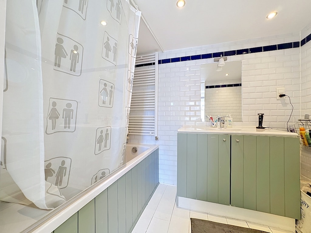 Salle de bain moderne à Londres avec baignoire, carrelage métro et meuble vasque vert sauge
